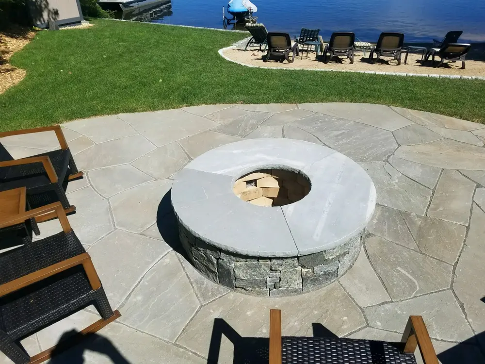 Waterfront fire pit patio with stone seating and lake views