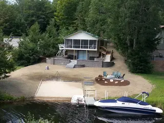 Aerial view of waterfront property with beach and fire pit gathering space
