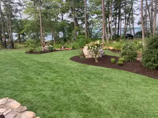 Boulder and hydrangea planting island on lakefront lawn