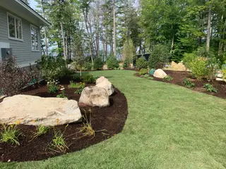 Boulder planting bed along curved lawn near lakeside home