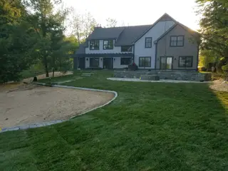 Completed home landscape with stone retaining wall and mature trees