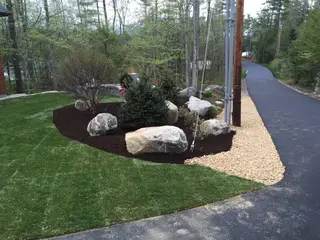 Entry landscape with boulders, evergreens, and gravel edging