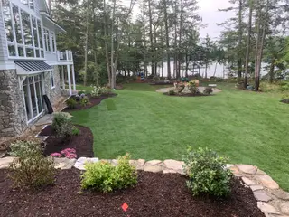 Expansive lakefront lawn with fire pit patio