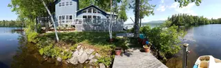 Lakefront home aerial view with dock, boathouse, and mountain backdrop