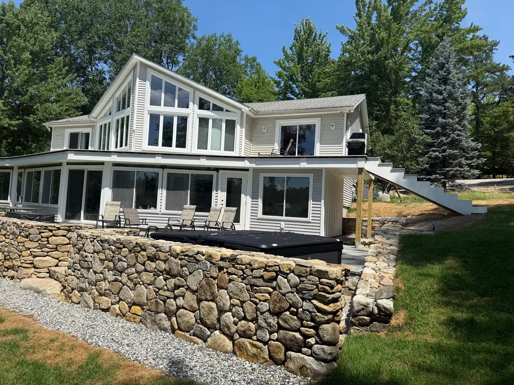 Lakeside home with finished stone retaining wall and patio