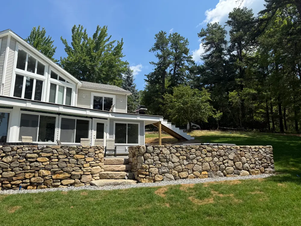 Lakeside home with a screened porch, stone steps, and finished landscaping