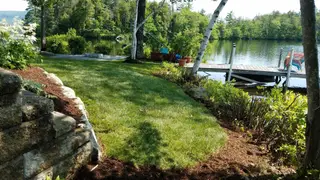 Lakeside landscape with established lawn, stone wall, and dock access
