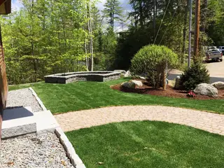 Landscape with curved stone retaining bench and brick patio