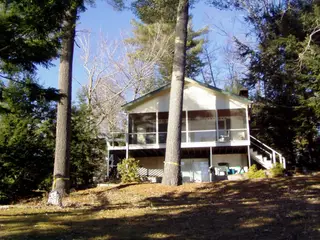 Modern house elevated on concrete supports in wooded setting