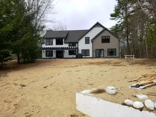 New farmhouse-style home with stone hardscape and gravel foundation