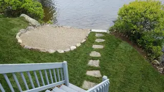 Stepping stone pathway leading to scalloped stone patio at water's edge