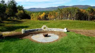 Stone fire pit gathering space with mountain and autumn forest views