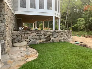 Stone foundation wall with white phlox planting bed