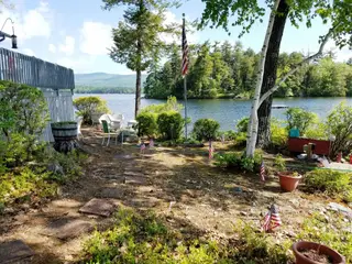 Waterfront gathering area with flagpole, dock, and natural shoreline plantings