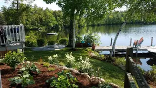 Waterfront property with dock, moored boats, and ornamental plantings