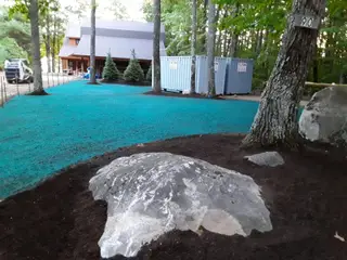 Hydroseeded yard with boulder outcrop near lakeside cabin