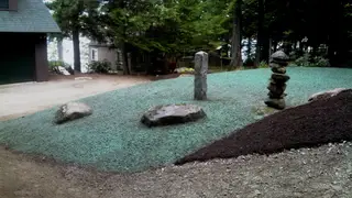 Hydroseeded yard with stone cairn and granite marker