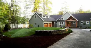 Sprinkler watering front lawn near stone wall