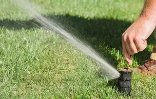 Technician adjusting sprinkler head spray pattern