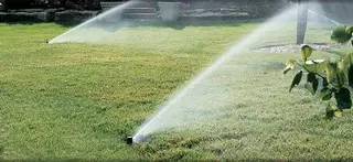 Two sprinkler heads by stone edging