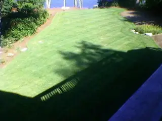 Aerial view of striped lawn sloping to lake