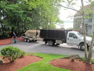 Crew running mulch blower truck at lakeside property