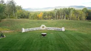 Curved stone wall and fire pit on striped lawn