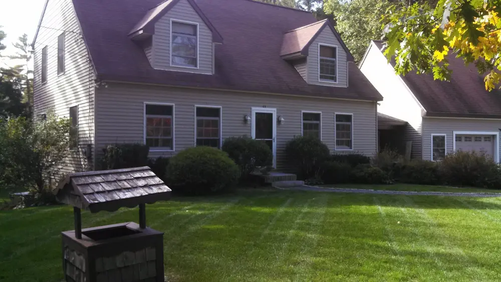 Striped front lawn with a wishing well planter