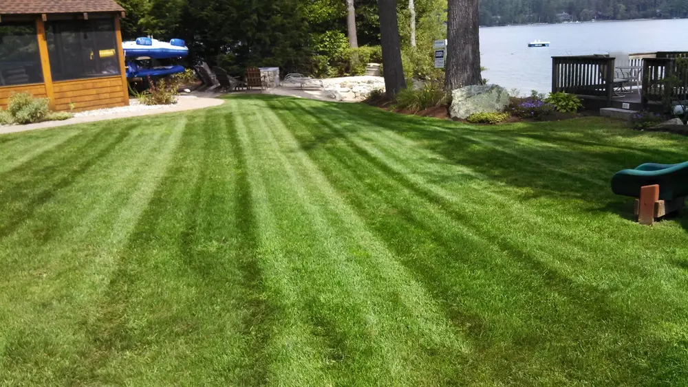 Striped lakeside lawn with a patio and boathouse