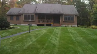Striped lawn leading to ranch-style home porch