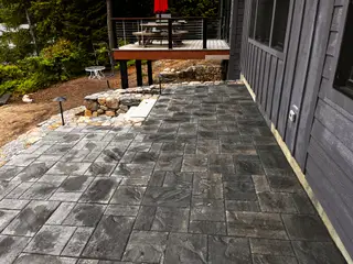 Bluestone paver patio with red umbrella and deck above