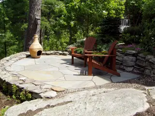 Circular stone patio with chiminea and Adirondack chairs