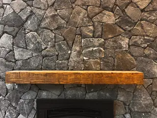 Close-up of dark stone fireplace and mantel beam