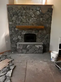 Dark stacked stone fireplace wall with light hearth
