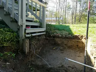 Excavated foundation area beneath deck stairs