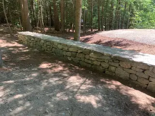 Fieldstone retaining wall bordering gravel drive