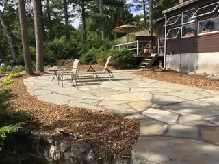 Flagstone patio with sling chairs by cabin