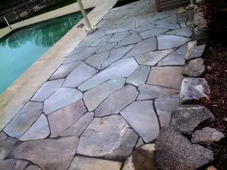Flagstone pool deck beside boulder wall