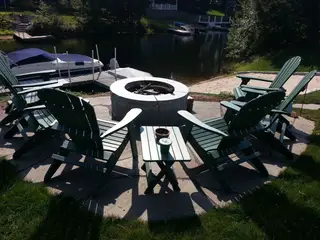 Green Adirondack chairs around fire pit near lake