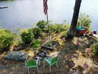 Lakeside campfire ring with lawn chairs and flag