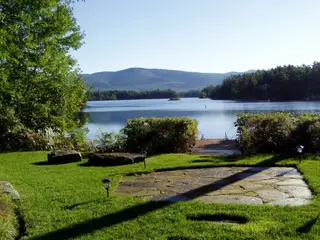 Lakeside lawn with stone patio and dock view