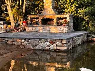 Lakeside stone fireplace patio at golden hour