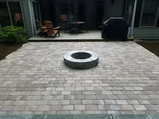 Paver patio with built-in fire pit ring behind home
