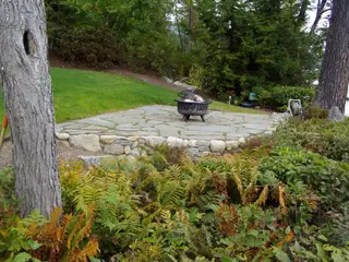 Round fire bowl on flagstone patio with hose reel