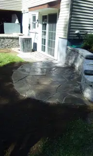 Round flagstone patio beside stone retaining wall steps