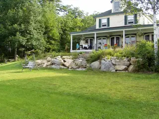 Rustic boulder steps climbing to farmhouse porch