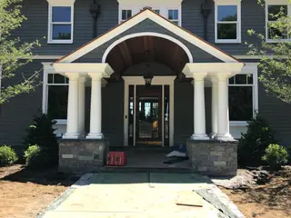 Stone-clad column bases at covered entry portico