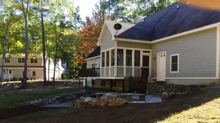 Stone fire pit patio behind house in fall