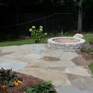 Stone fire pit patio bordered by hydrangeas