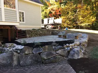Stone retaining wall patio under construction in fall